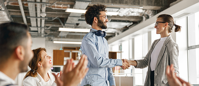 Employee Engagement - Man shaking hands with woman and staff happy